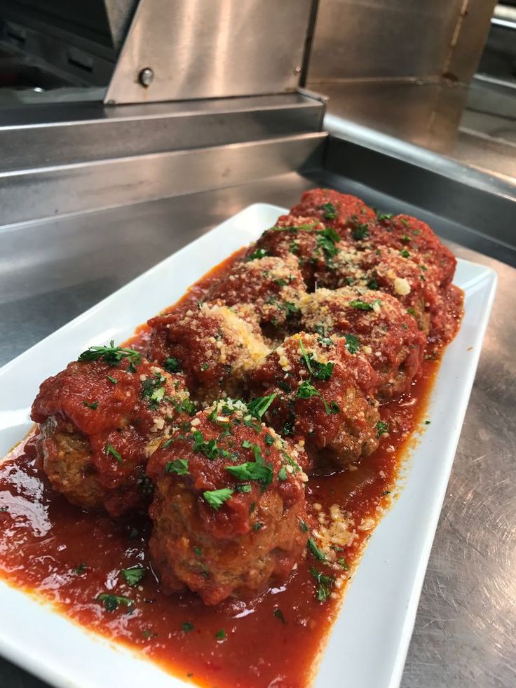 meatballs covered in marinara sauce on a white plate