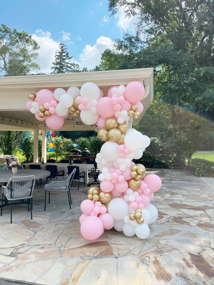 the balloon arch is decorated with pink, white and gold balloons for an outdoor party