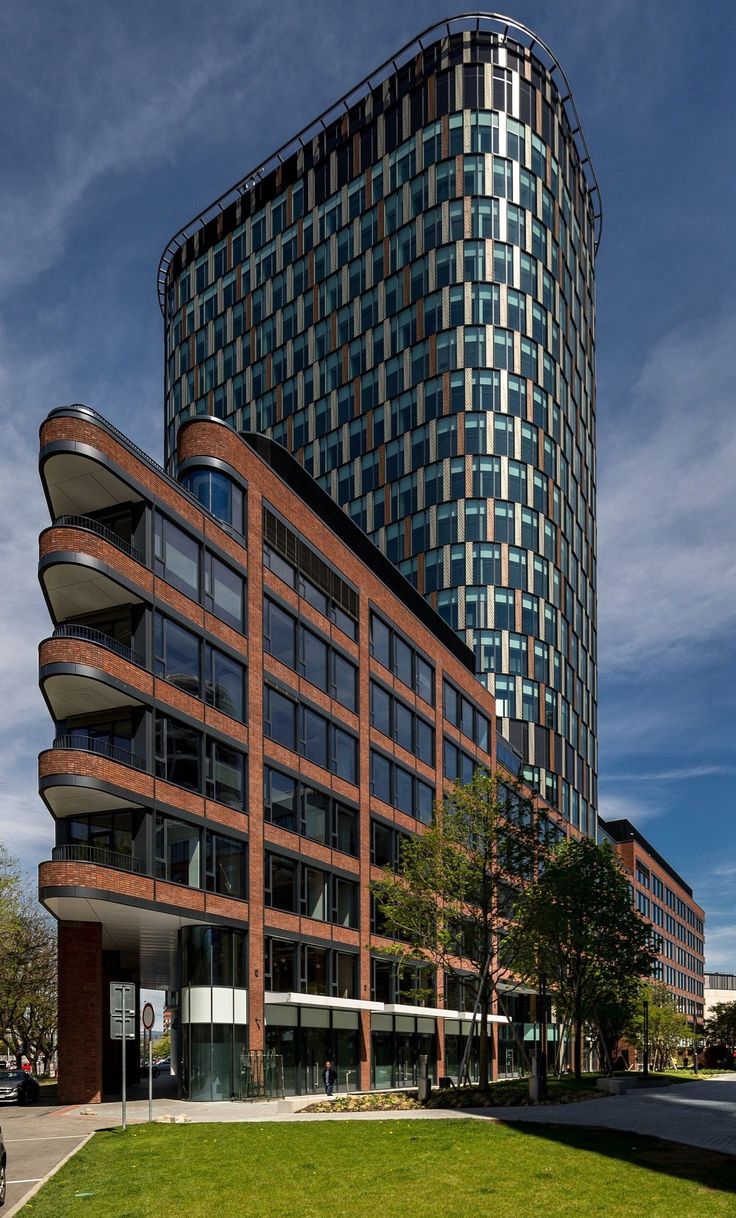 a tall building with many windows on top of it's sides and grass in the foreground