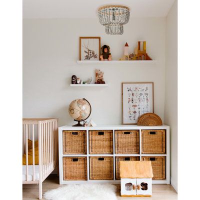 a baby's room with white walls and wicker baskets on the dressers