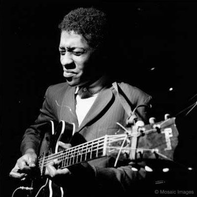 a black and white photo of a man playing an acoustic guitar