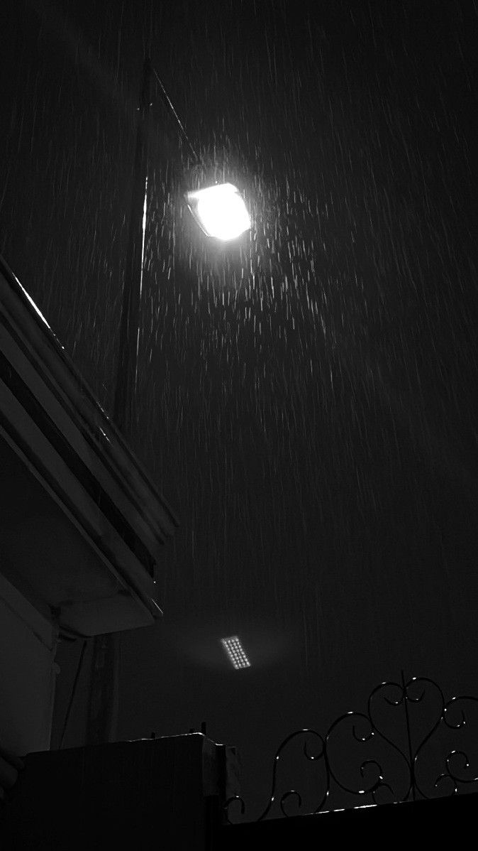 a street light in the dark with rain coming down on it's roof and window sill