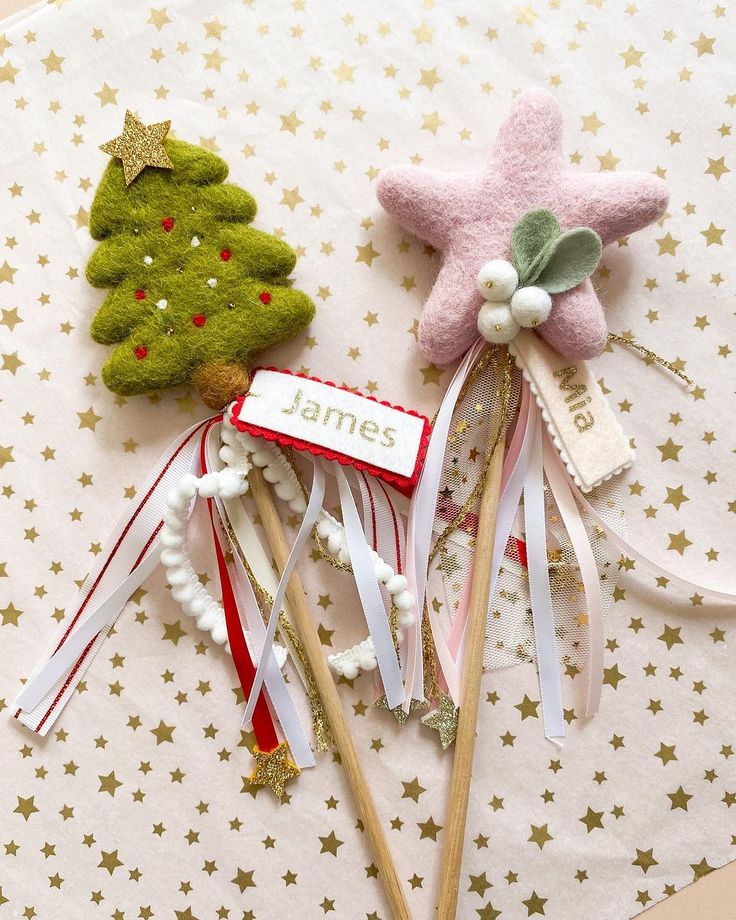 two small christmas trees on top of some toothpicks with bows and ribbons attached to them