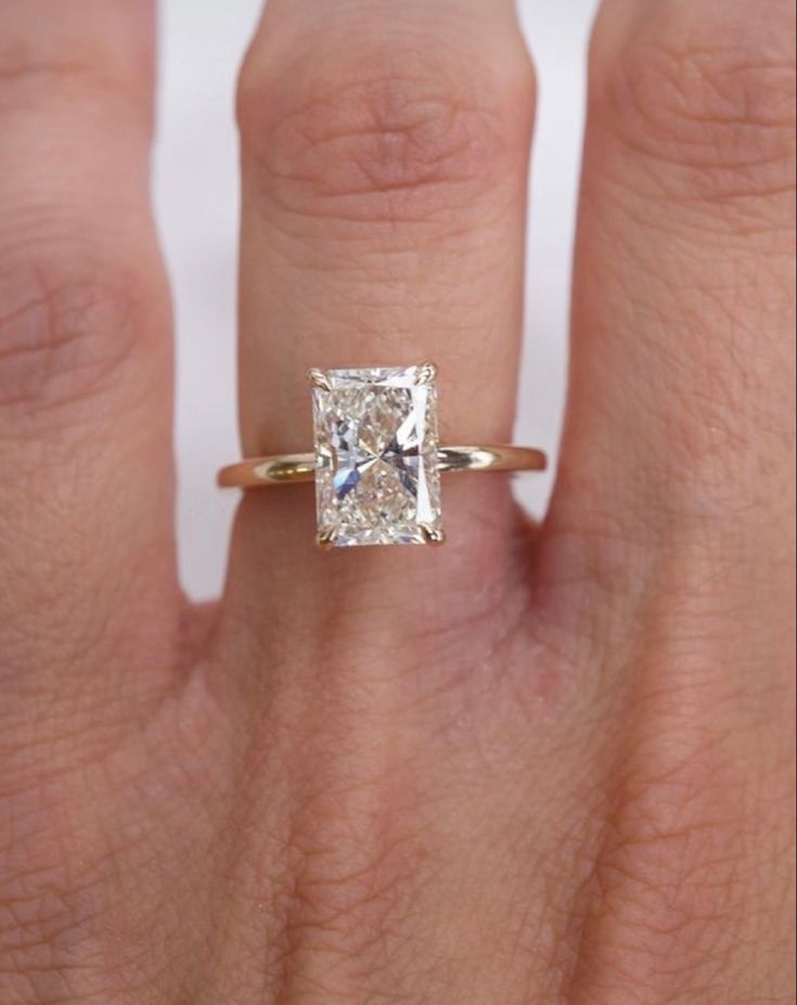 a woman's hand with a diamond ring on top of her finger and an engagement band