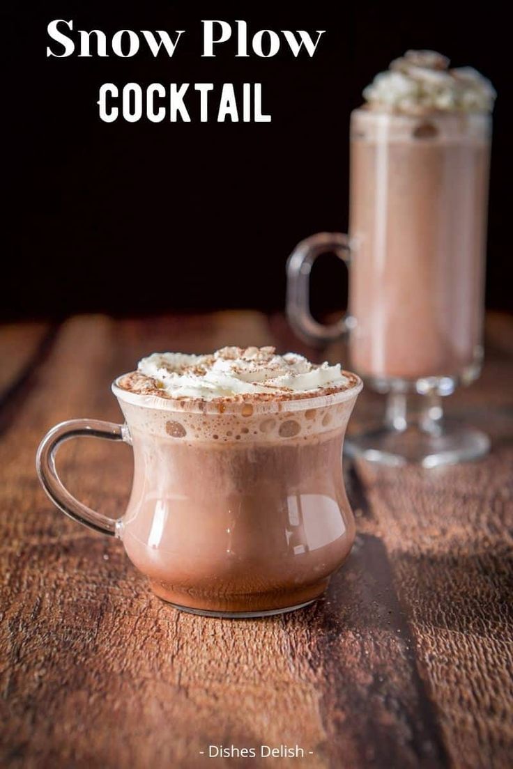 two glasses filled with hot chocolate drink on top of a wooden table next to each other