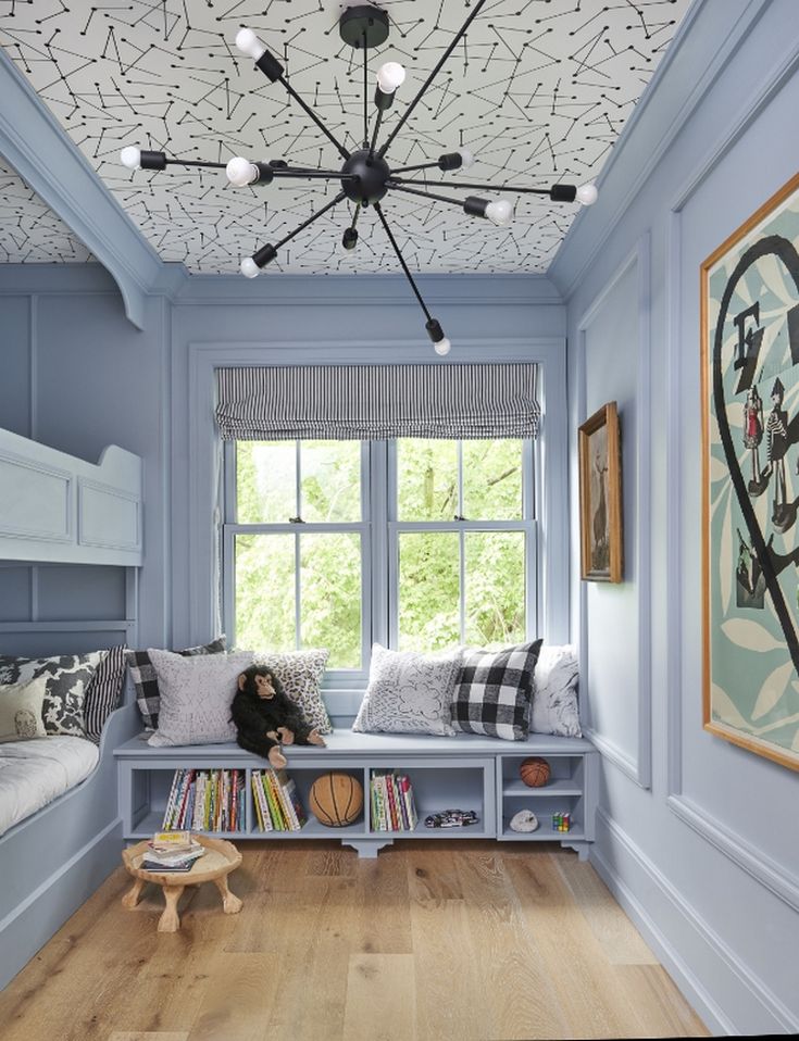 a room with blue walls and wooden floors, bookshelves on either side of the window