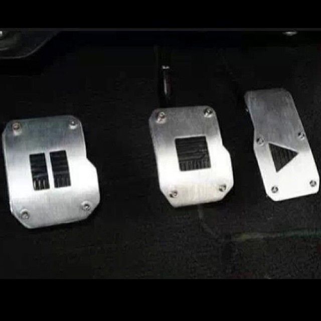 three metal pedals sitting next to each other on a black cloth covered flooring