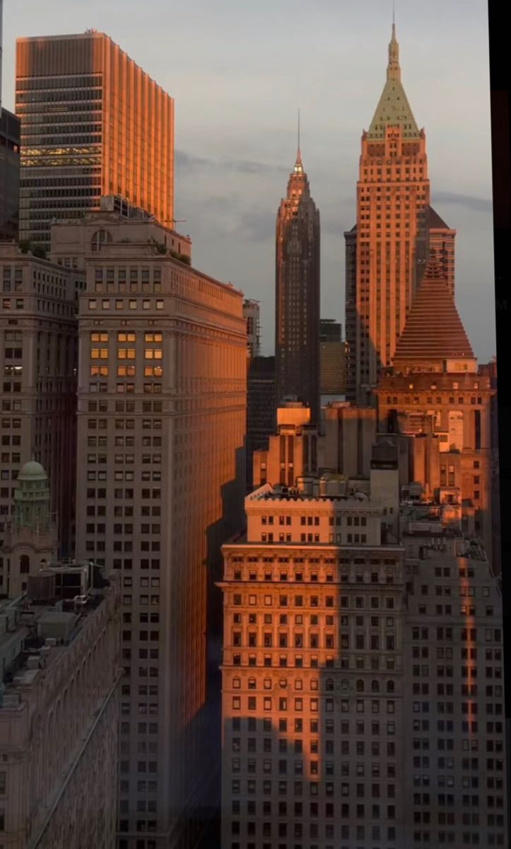 the sun is setting on top of some tall buildings in new york city, ny