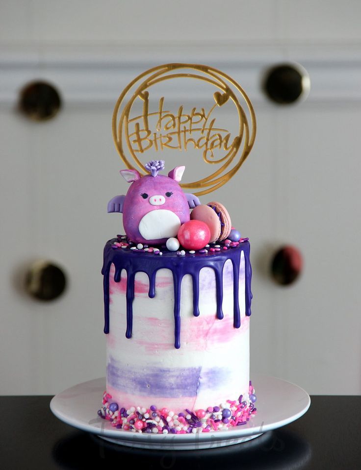 a birthday cake with an animal on top and purple icing dripping down the side