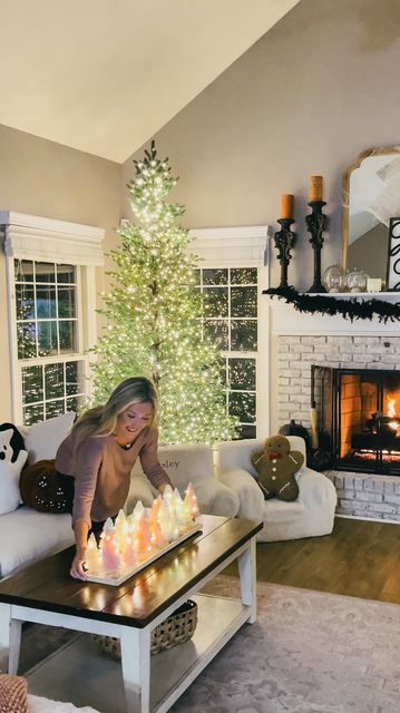 a woman bending over to blow out candles on a cake in front of a christmas tree