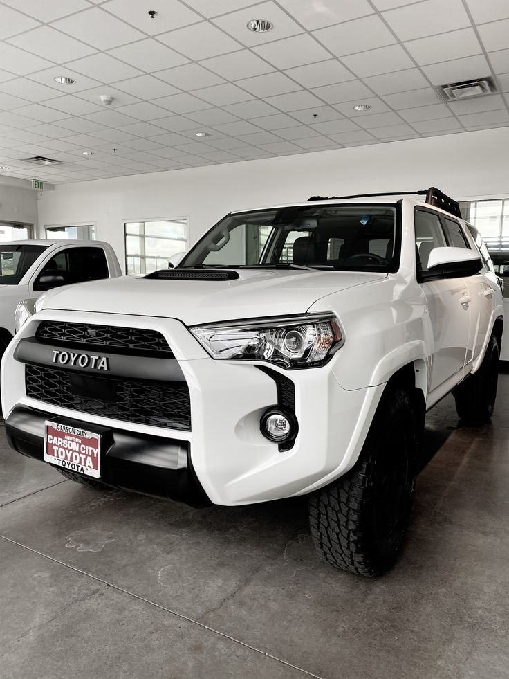 two white toyota trucks are parked in a showroom