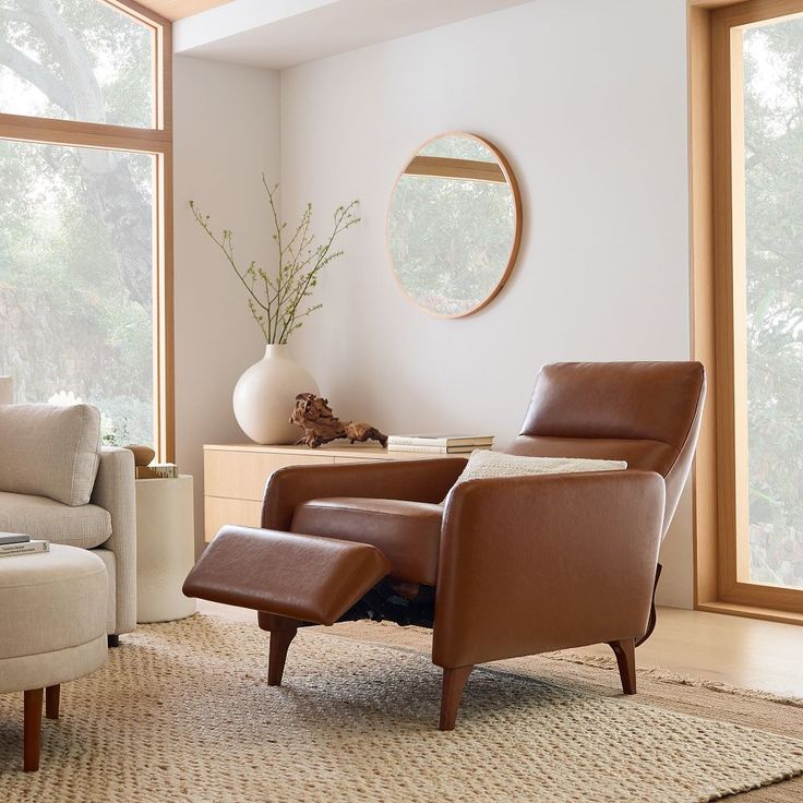 a living room with two chairs and a round mirror