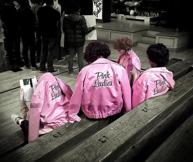 three people in pink jackets sitting on a bench with their backs turned to the camera