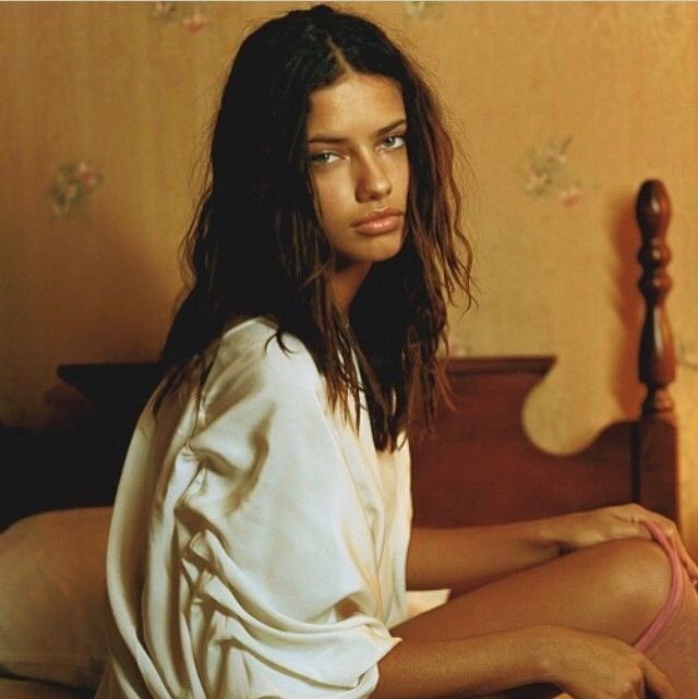 a woman sitting on top of a bed next to a wooden headboard