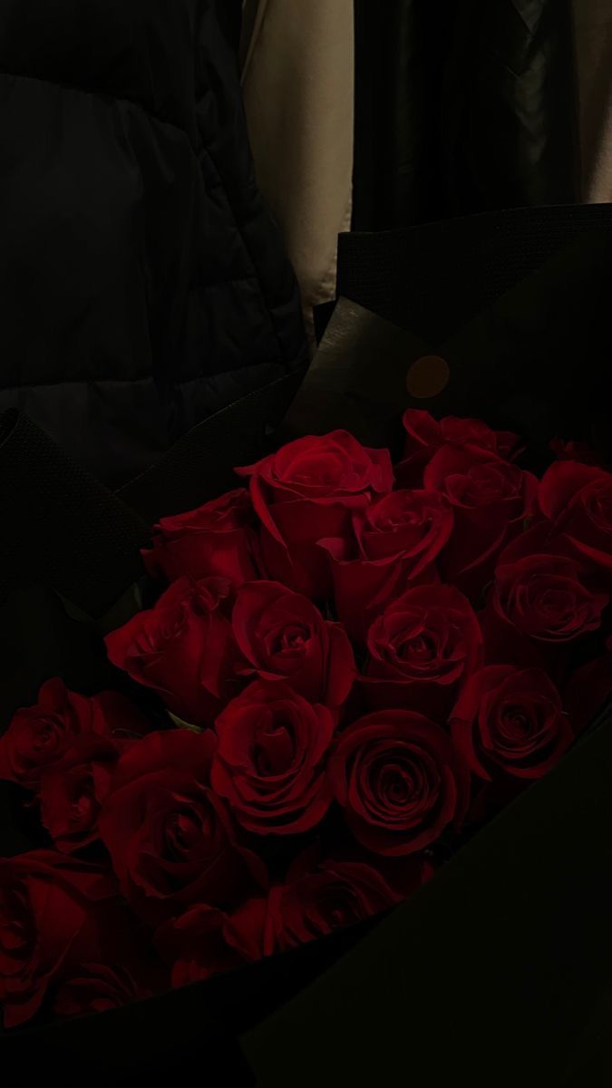 a bunch of red roses in a black box