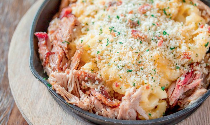 a skillet filled with macaroni and cheese covered in meat