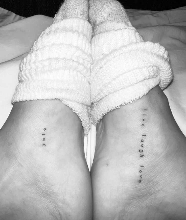 two women's legs with small tattoos on their ankles, both showing the same word