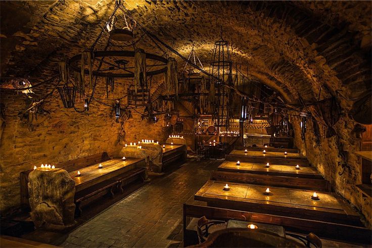 a dimly lit restaurant with candles on the tables and stone walls, along with wooden benches