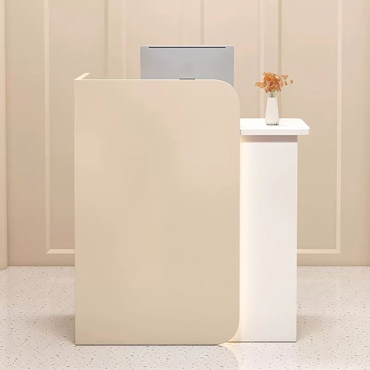 a white table with a vase and computer monitor on it