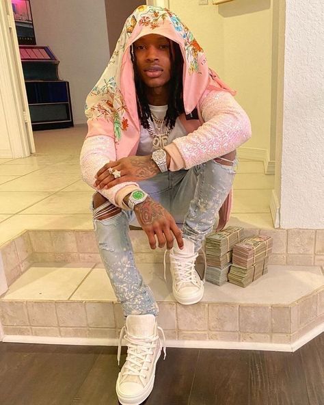 a man sitting on top of a step wearing white sneakers and a pink hoodie