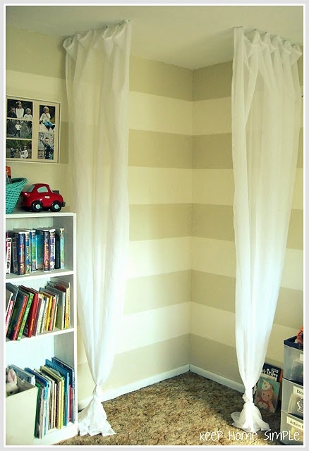 a room with striped walls and white curtains