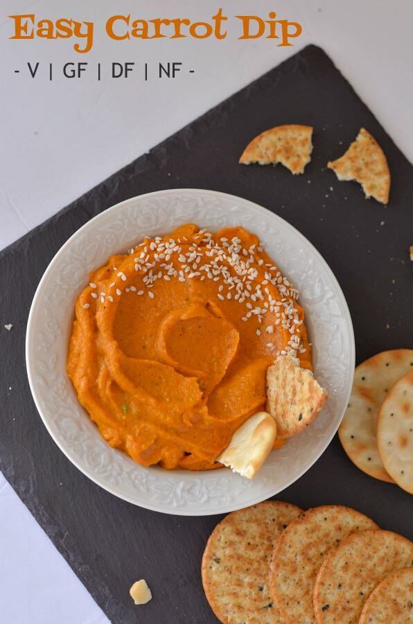 an easy carrot dip with crackers and cheese on a black slate board next to crackers