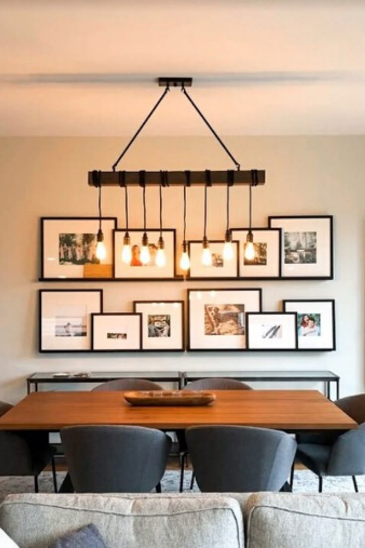 a dining room table with chairs and pictures on the wall above it in front of a couch