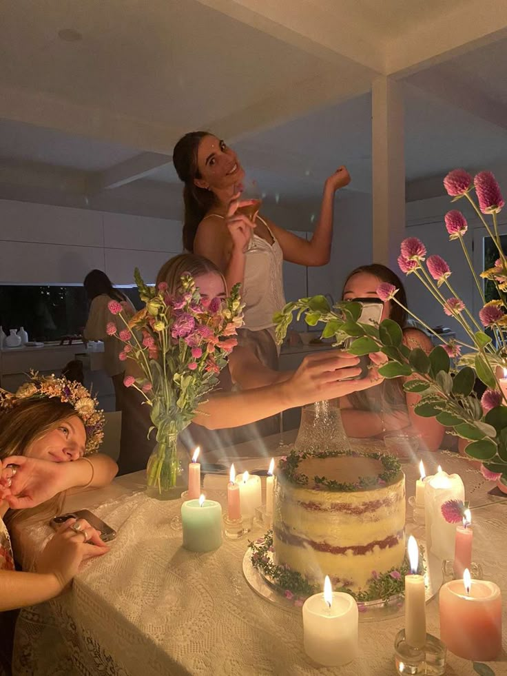 a group of people sitting around a table with a cake and candles in front of them