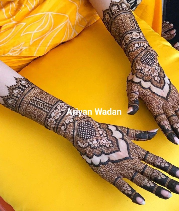 a woman's hands with hennap on them sitting on a yellow chair