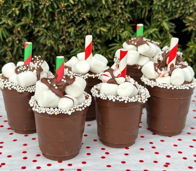 chocolate cups with marshmallows and candy canes in them on a table