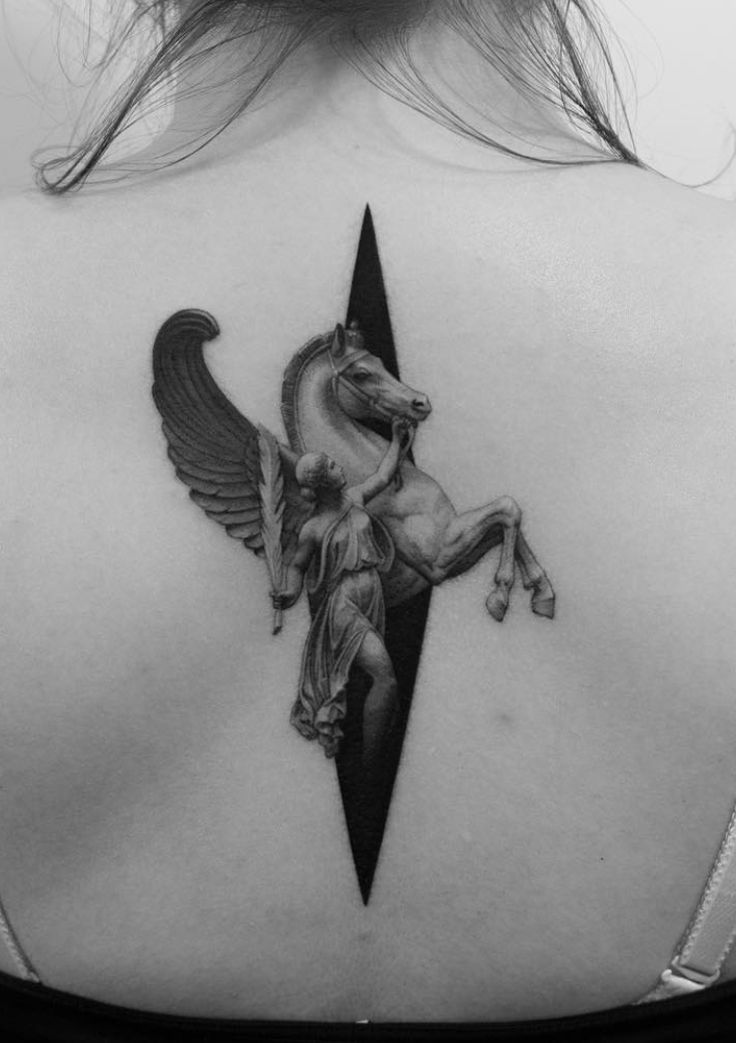 the back of a woman's shoulder with an angel and horse tattoo on it