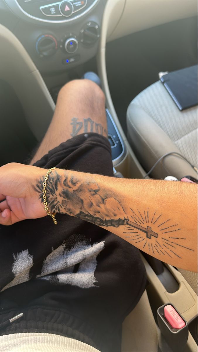 a person with tattoos on their arm sitting in a car