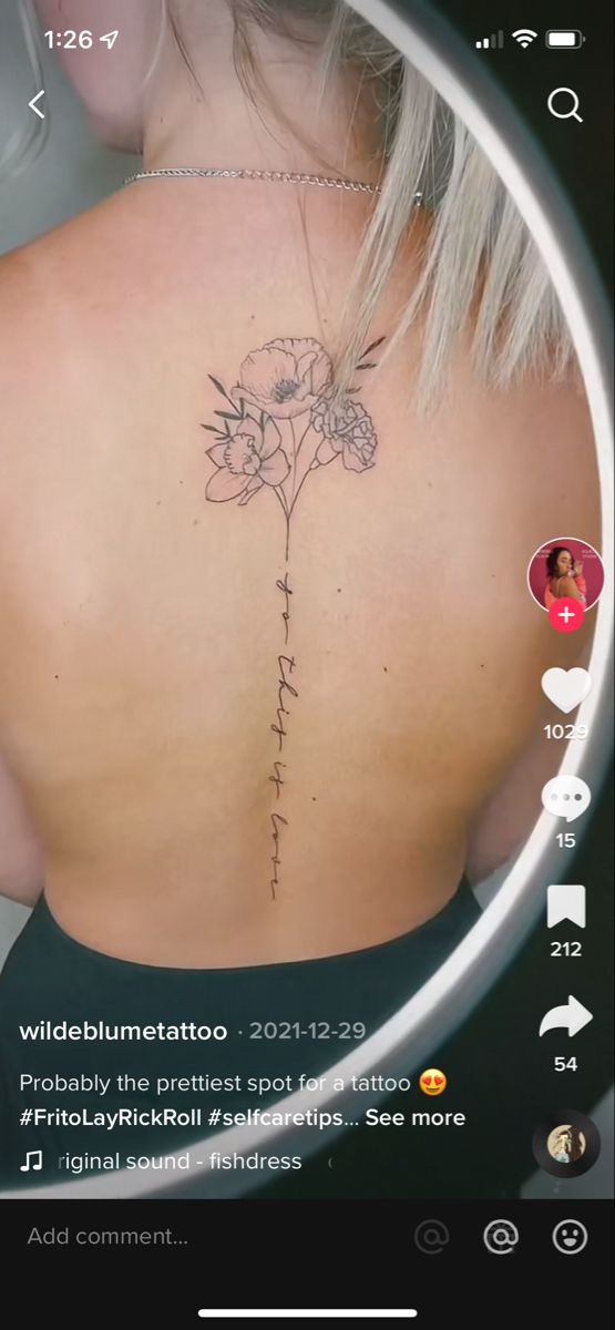 the back of a woman's upper back tattoo with flowers on her left side