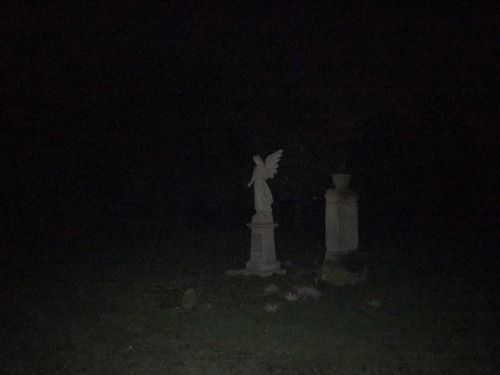 two statues in the dark with one angel on it