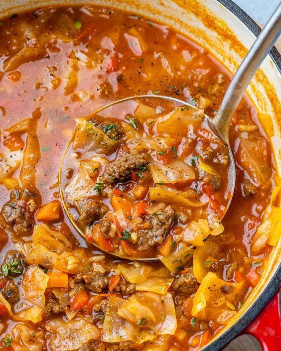 a ladle full of soup with meat and vegetables being spooned into the bowl