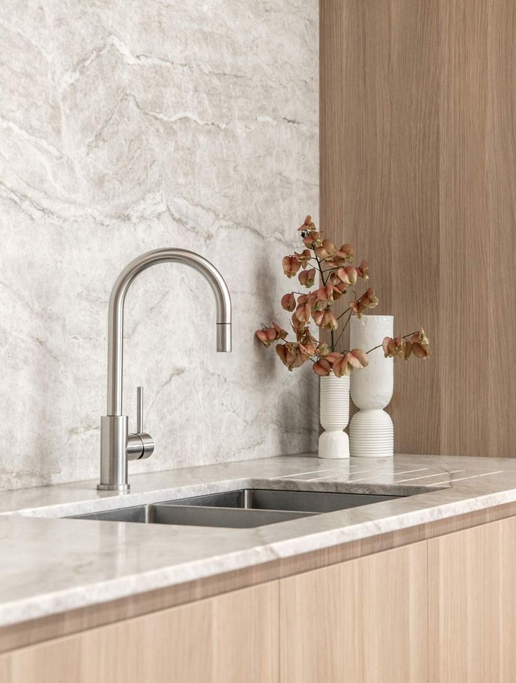 a kitchen with marble counter tops and white vases on the sink's edge