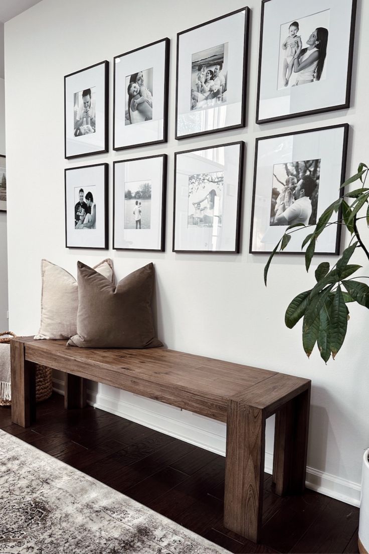 a wooden bench sitting in front of a wall with pictures on the wall above it