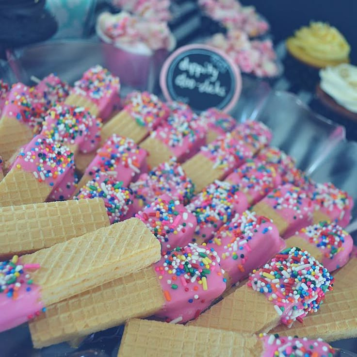 ice cream cones with sprinkles and pink frosting are on display in a bakery