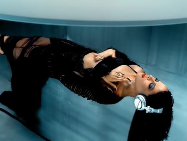 a woman with black hair and piercings laying down on a blue surface in an empty room