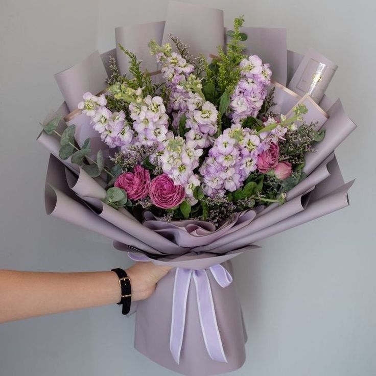 a bouquet of flowers is being held by a woman's hand on the wall