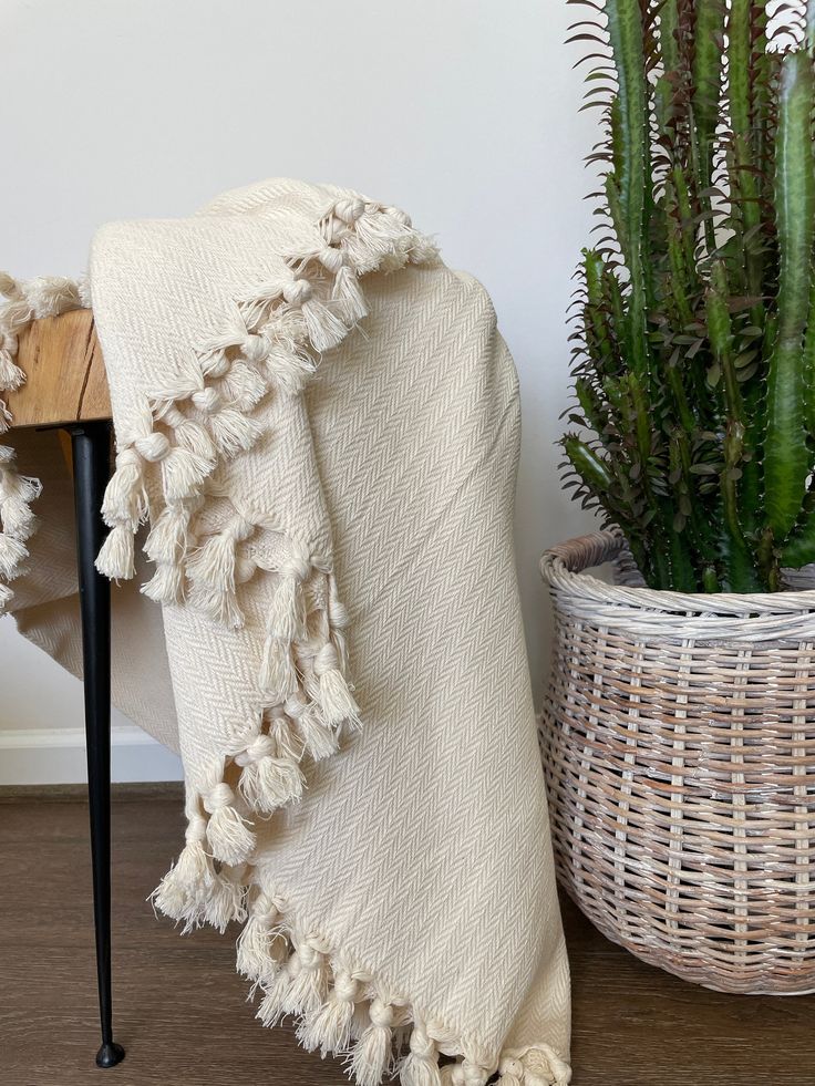 a white blanket sitting on top of a wooden floor next to a potted plant