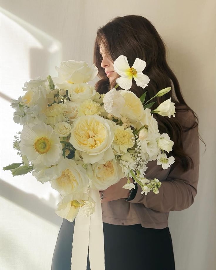 a woman holding a bouquet of white and yellow flowers