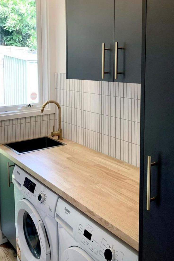 a washer and dryer in a small room with wooden counter tops on the counters