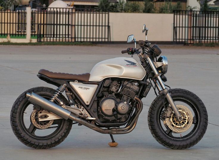 a white motorcycle parked on top of a cement parking lot next to a fenced in area