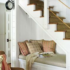 a living room filled with furniture and a stair case in front of a couch next to a window