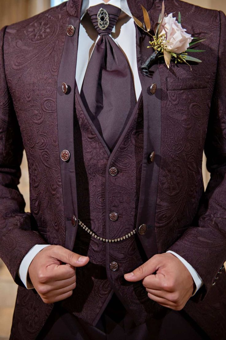 a man in a purple suit with a flower on his lapel and black tie