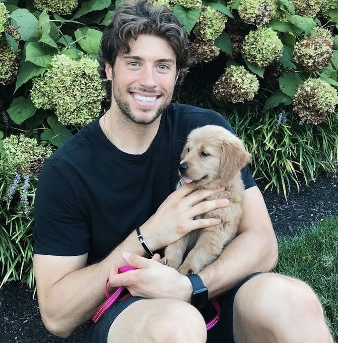 a man sitting on the ground holding a puppy in his lap and smiling at the camera