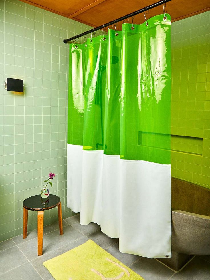 a green shower curtain in a bathroom with a yellow rug on the floor next to it