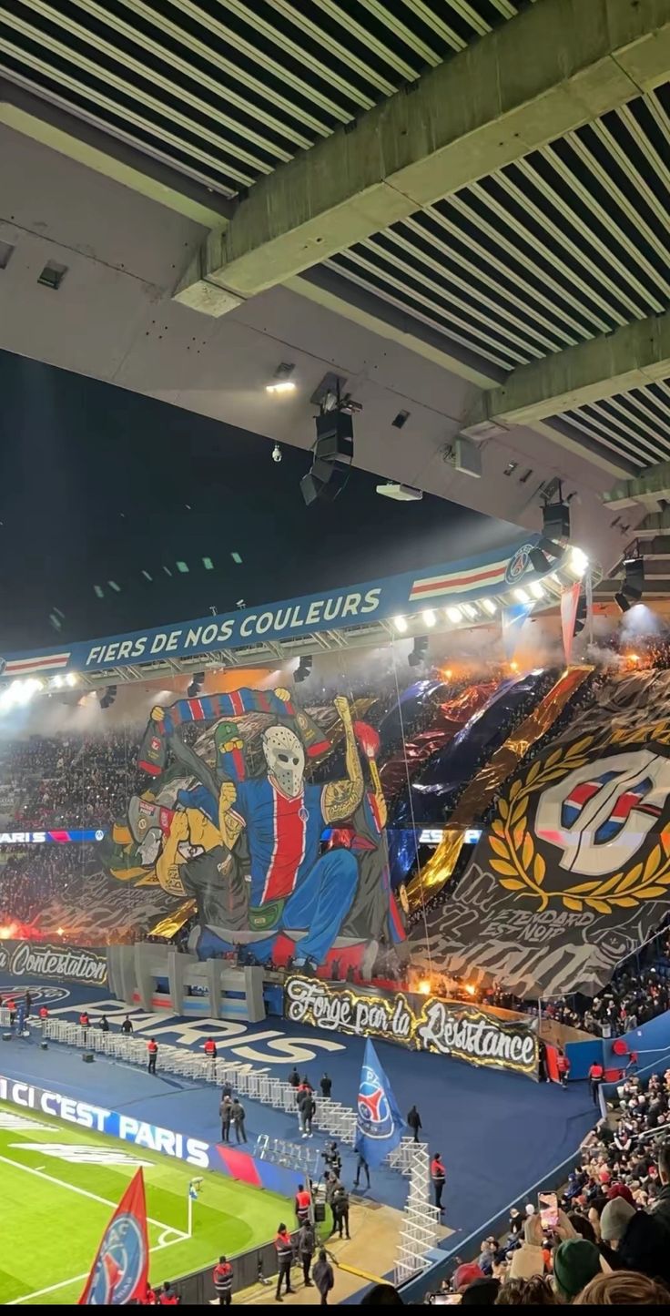 a stadium filled with lots of people sitting on top of a blue field covered in banners