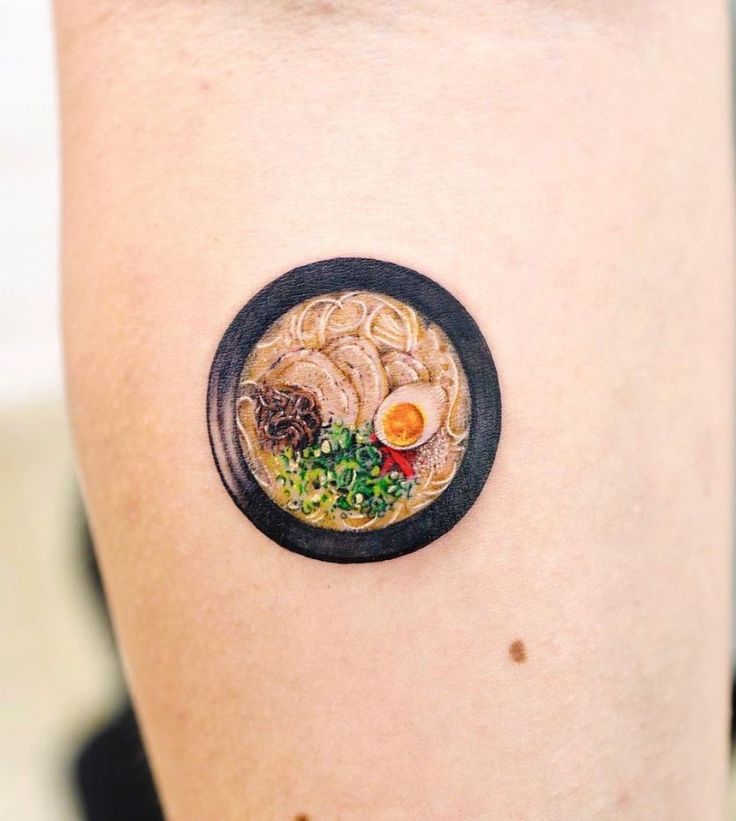 a woman's arm with a plate of food tattooed on the back of it